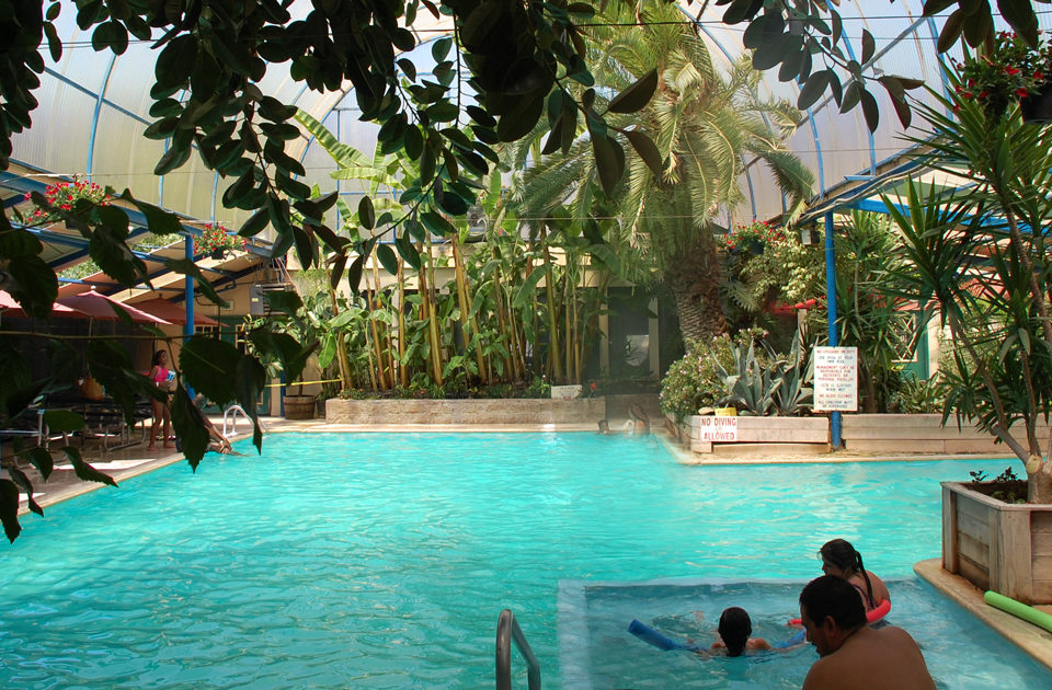 interior of hot spring pool with bright blue water and tropical trees