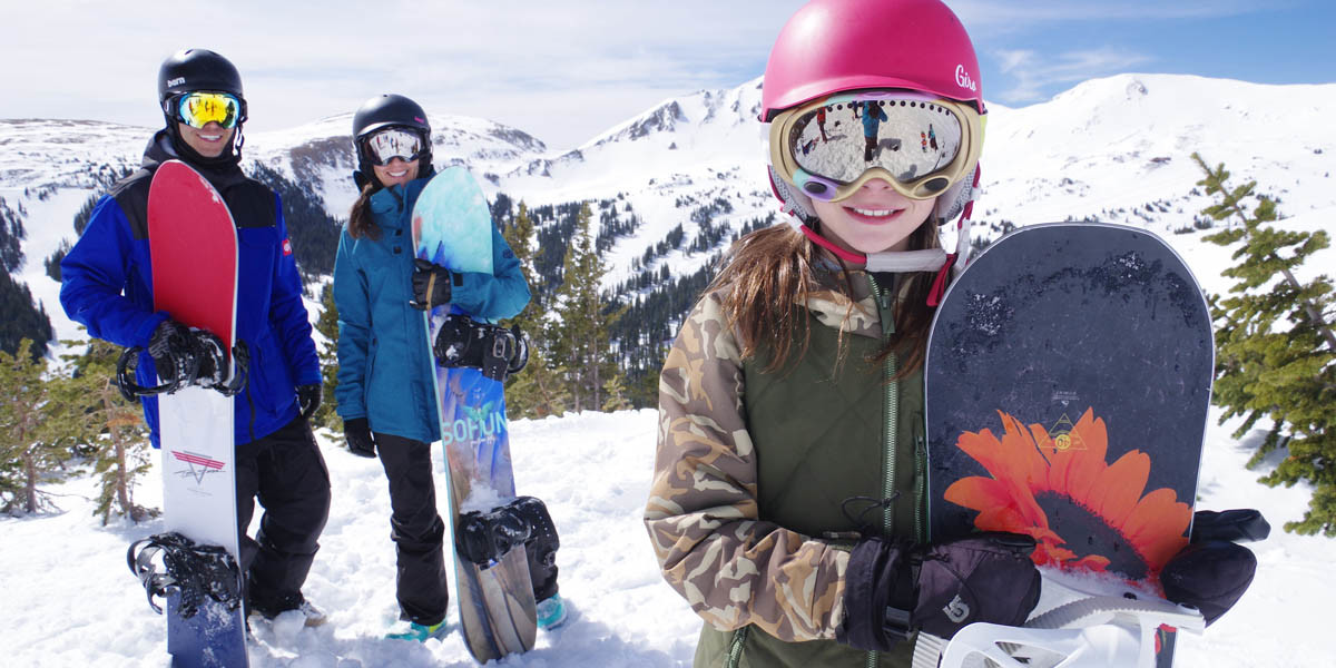 Snowboarding family pose with their snowboards.