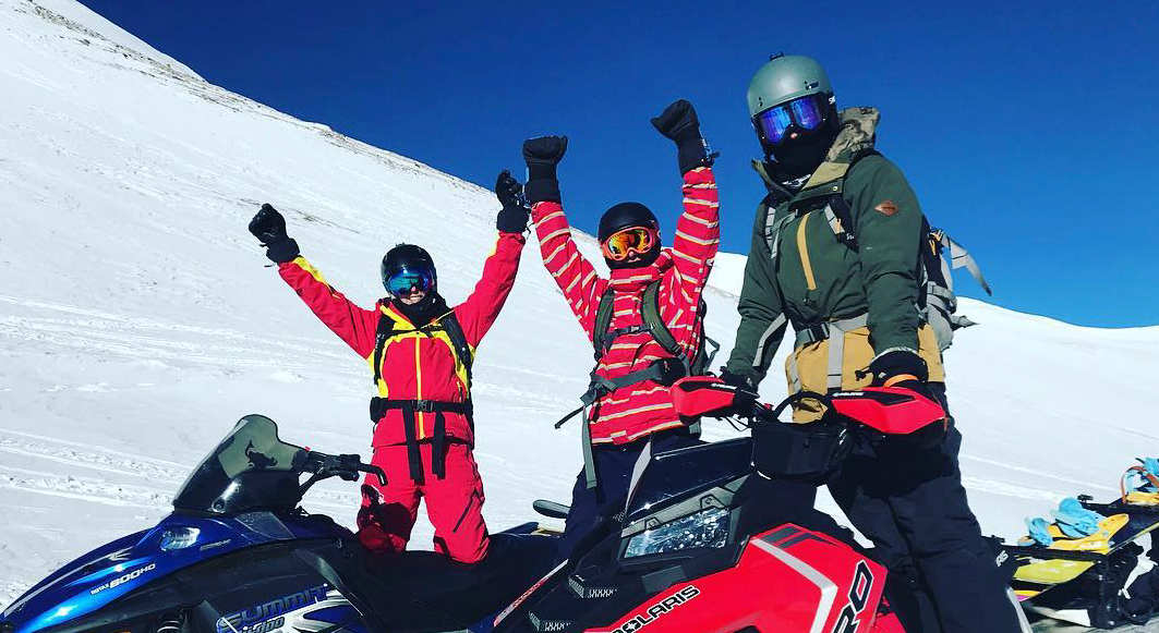 people on snowmobiles celebrating
