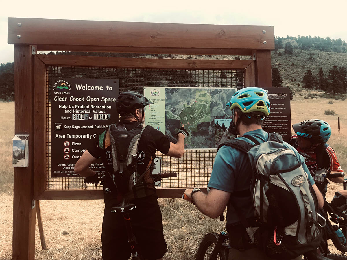Three bikers check out Clear Creek’s trail map to get orientated and prepare for an ultimate high-mountain biking trek.
