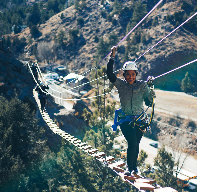 Person climbing on the ropes and nets of a giant suspended bridge.